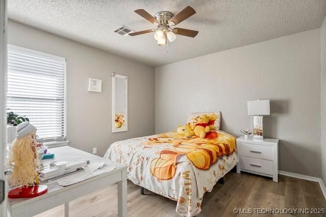 bedroom featuring ceiling fan, visible vents, a textured ceiling, and wood finished floors