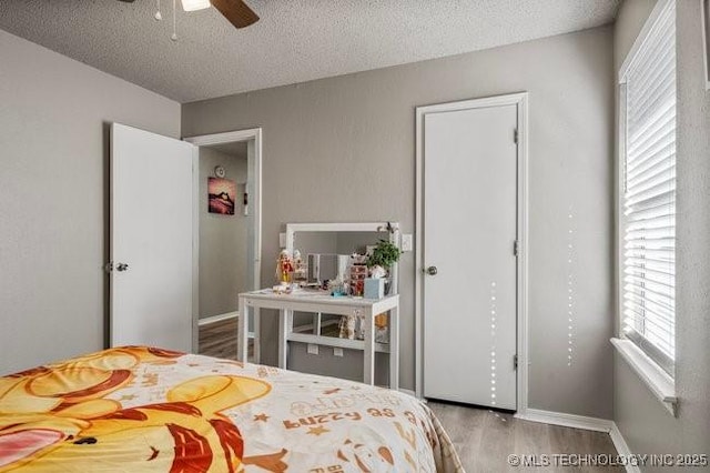 bedroom with baseboards, a textured ceiling, and wood finished floors