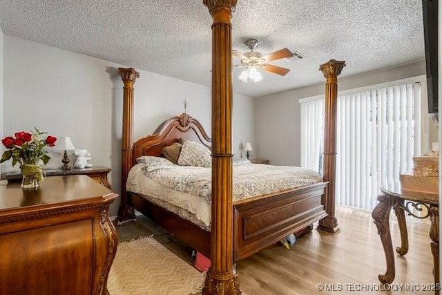 bedroom with visible vents, ceiling fan, decorative columns, wood finished floors, and a textured ceiling