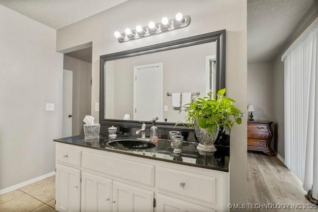 bathroom with vanity, baseboards, and a textured ceiling