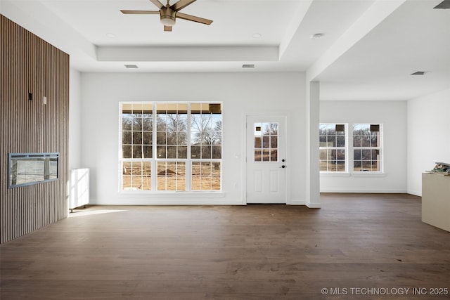 interior space featuring dark wood finished floors, visible vents, ceiling fan, and a tray ceiling