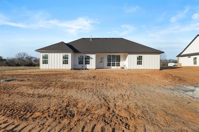 back of house featuring board and batten siding and roof with shingles