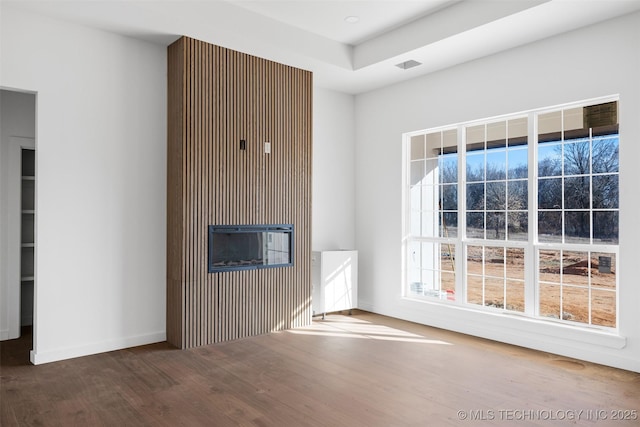 spare room featuring a tray ceiling, visible vents, baseboards, and wood finished floors