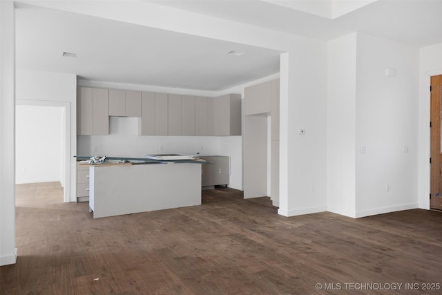 kitchen featuring a kitchen island, baseboards, gray cabinets, modern cabinets, and dark wood-style flooring