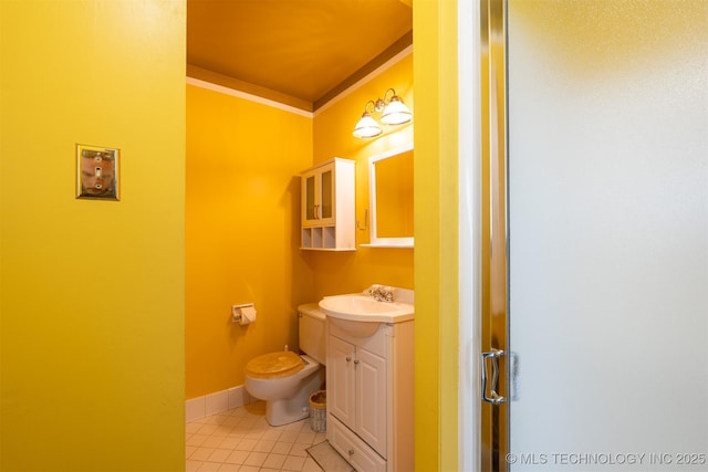 bathroom featuring vanity, baseboards, tile patterned flooring, crown molding, and toilet