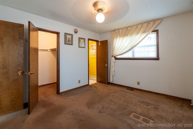 unfurnished bedroom with carpet, visible vents, baseboards, a closet, and a walk in closet