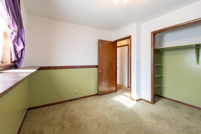 unfurnished bedroom featuring a closet, baseboards, and carpet flooring