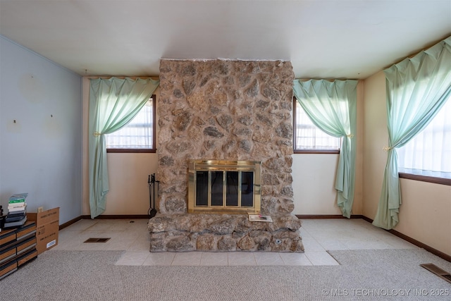 unfurnished living room with a wealth of natural light, visible vents, light colored carpet, and a stone fireplace