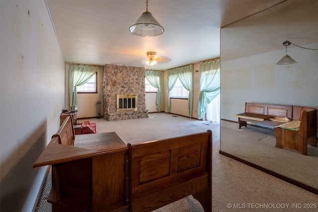 carpeted living area featuring a wealth of natural light, baseboards, and a stone fireplace