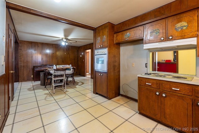 kitchen with white appliances, brown cabinetry, light countertops, and under cabinet range hood