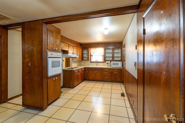 kitchen with visible vents, brown cabinets, a sink, white appliances, and light countertops