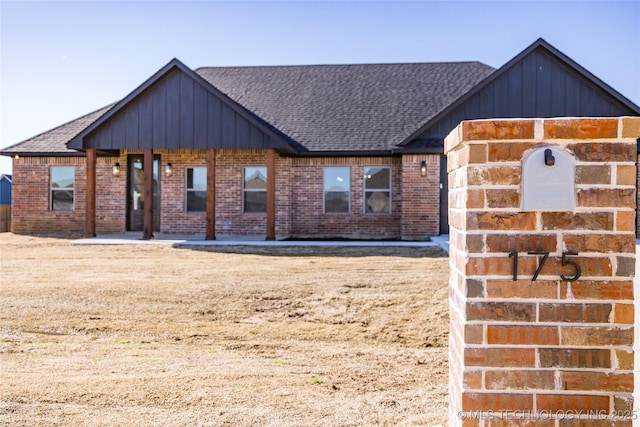 view of front facade with brick siding and roof with shingles