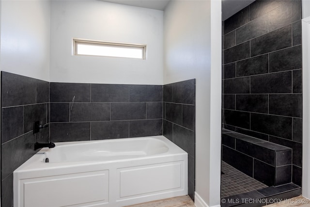 full bath with a garden tub and a tile shower