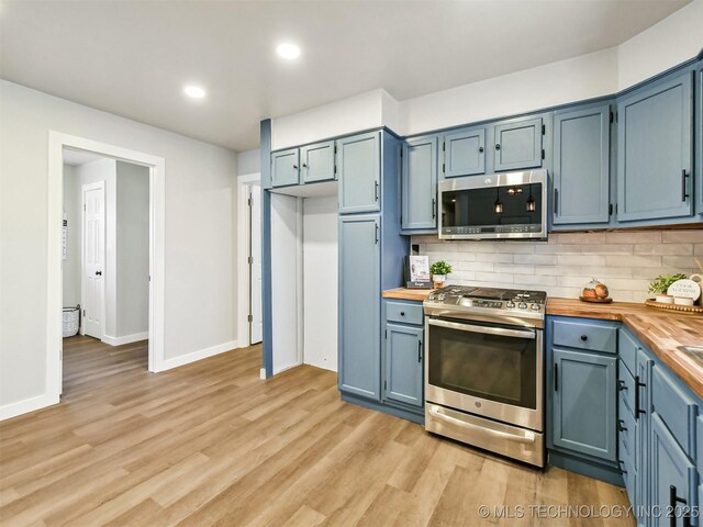 kitchen with light wood finished floors, butcher block counters, decorative backsplash, stainless steel appliances, and blue cabinets