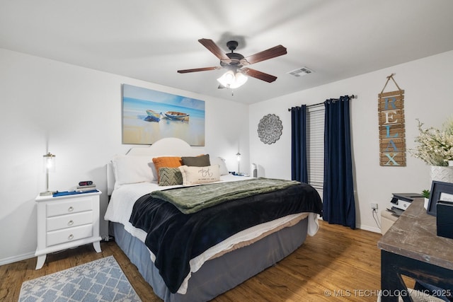 bedroom with baseboards, wood finished floors, visible vents, and ceiling fan