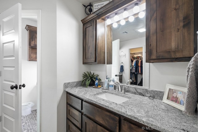 bathroom with vanity, a walk in closet, and visible vents