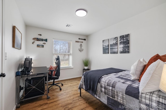 bedroom featuring visible vents, baseboards, and wood finished floors