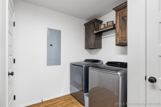 laundry room with electric panel, cabinet space, light wood-style floors, baseboards, and washing machine and clothes dryer