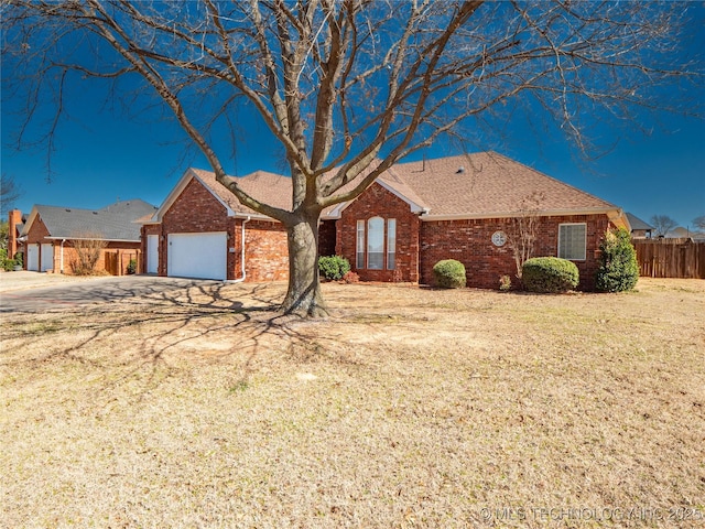 ranch-style home with brick siding, an attached garage, a front lawn, and fence