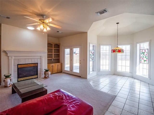 living area with built in shelves, visible vents, a fireplace, tile patterned floors, and carpet flooring