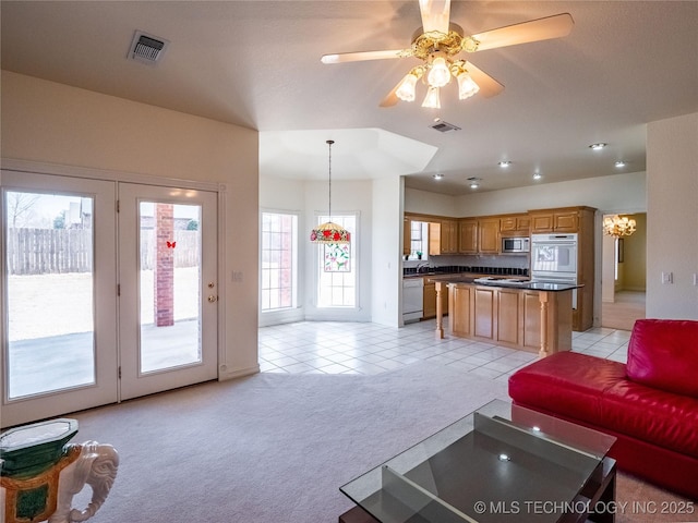 living room featuring light tile patterned floors, visible vents, light colored carpet, and ceiling fan with notable chandelier