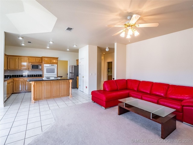 living area featuring light carpet, light tile patterned floors, visible vents, and ceiling fan