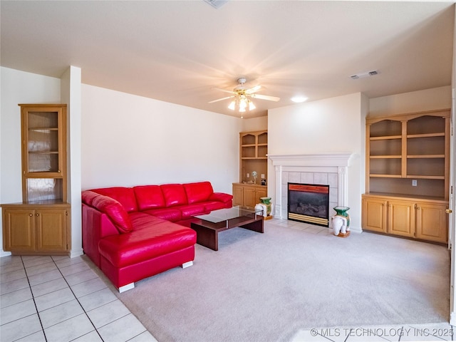 living room with visible vents, ceiling fan, light carpet, light tile patterned floors, and a tile fireplace