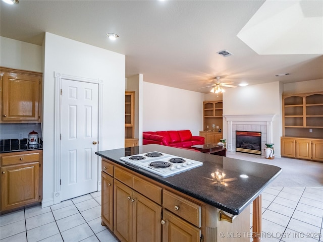 kitchen featuring visible vents, white electric cooktop, light tile patterned flooring, and a tiled fireplace