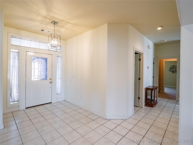 foyer with light tile patterned floors, visible vents, a chandelier, and baseboards