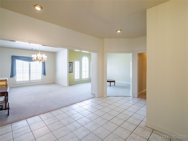 empty room featuring a notable chandelier, a healthy amount of sunlight, light tile patterned floors, and light carpet