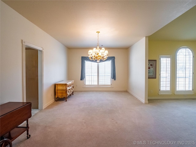 spare room featuring light carpet, plenty of natural light, and a chandelier