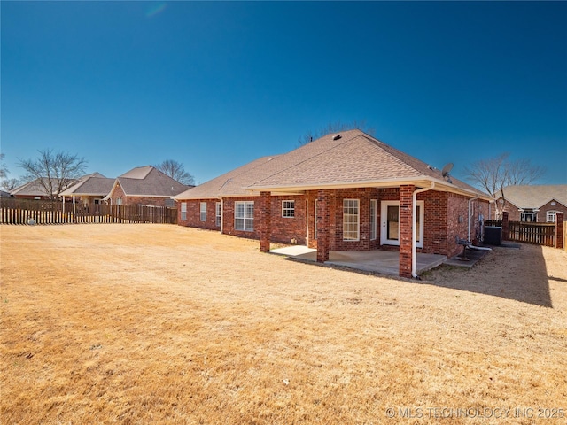 rear view of house with a yard, brick siding, a fenced backyard, and a patio area