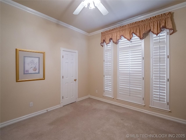 carpeted spare room featuring baseboards, a ceiling fan, and crown molding