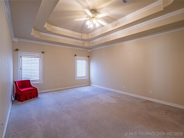 spare room with a raised ceiling, crown molding, carpet floors, and ceiling fan