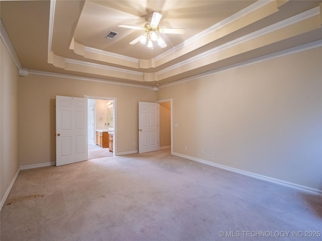 unfurnished bedroom featuring a tray ceiling, baseboards, visible vents, and ornamental molding