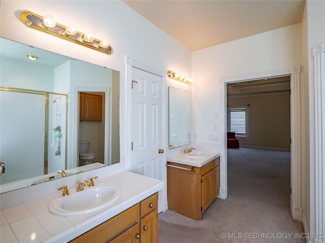 bathroom with a stall shower, toilet, two vanities, and a sink