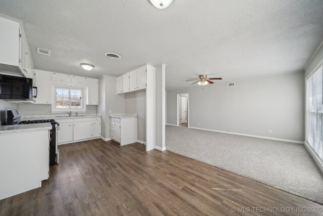 8930 E Marshall St, Tulsa, OK 74115 - kitchen featuring white cabinetry, gas range, visible vents, and black microwave