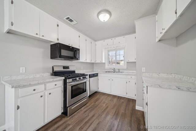 8930 E Marshall St, Tulsa, OK 74115 - kitchen featuring visible vents, dark wood-type flooring, appliances with stainless steel finishes, white cabinets, and light countertops
