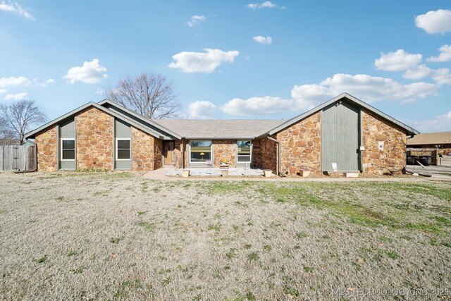 view of front of property featuring stone siding, a front lawn, and fence