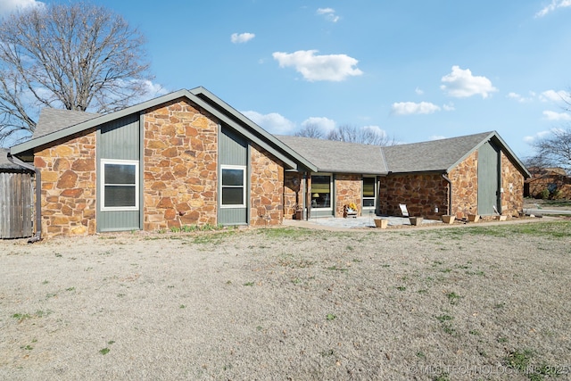 back of property with a patio area, stone siding, and fence