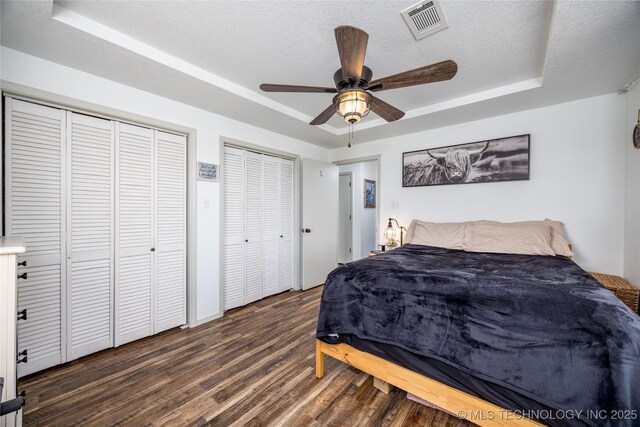 1522 Burney Cemetary, Calera, OK 74730 - bedroom with a tray ceiling, wood finished floors, a textured ceiling, visible vents, and two closets