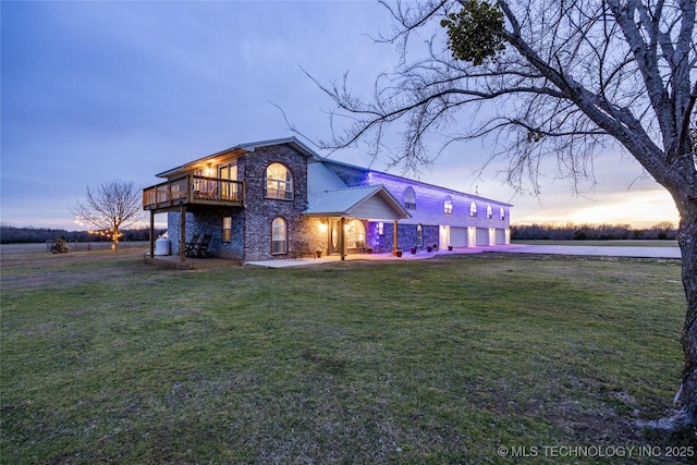 1522 Burney Cemetary, Calera, OK 74730 - front of house at dusk with a balcony, driveway, stone siding, and a yard
