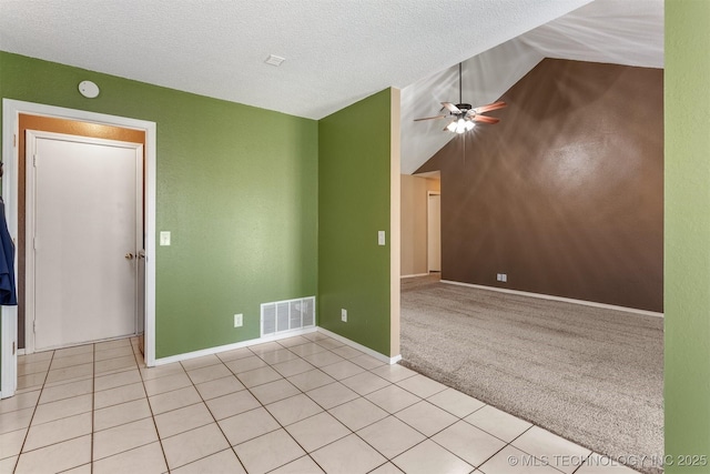 empty room with visible vents, ceiling fan, light colored carpet, lofted ceiling, and light tile patterned floors