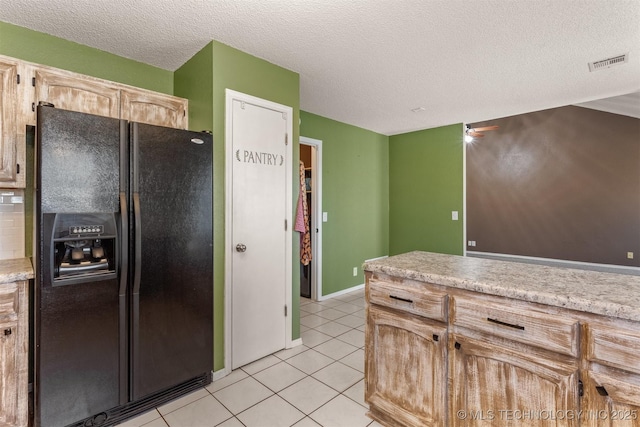 kitchen with visible vents, light tile patterned flooring, light countertops, black fridge with ice dispenser, and a textured ceiling