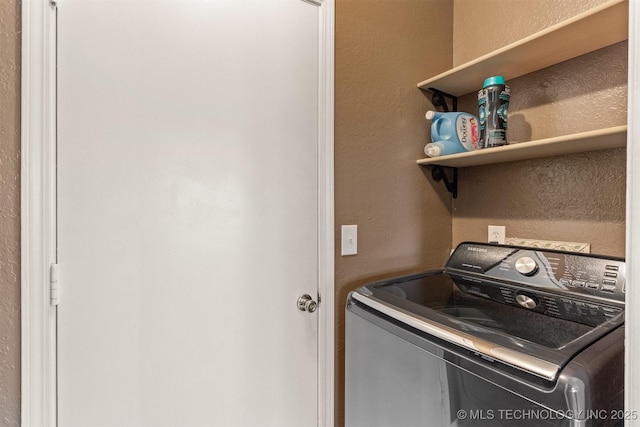 washroom featuring washer / dryer, a textured wall, and laundry area