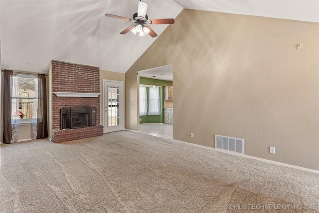 unfurnished living room featuring visible vents, carpet floors, a fireplace, high vaulted ceiling, and a ceiling fan