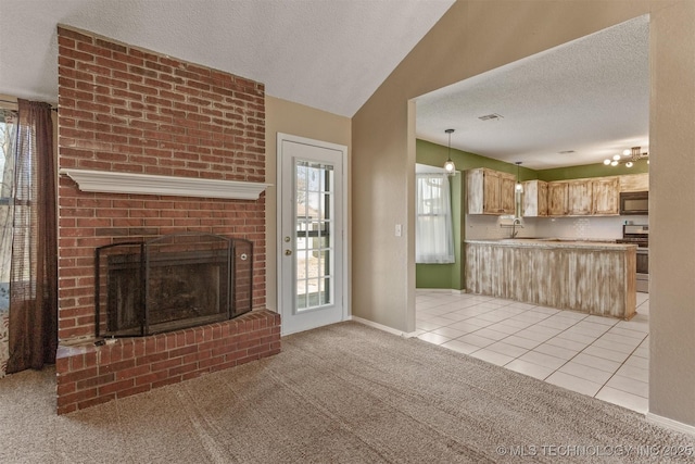 unfurnished living room featuring a sink, light carpet, a textured ceiling, and a fireplace