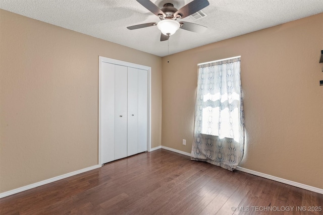 unfurnished bedroom with a closet, multiple windows, a textured ceiling, and wood finished floors