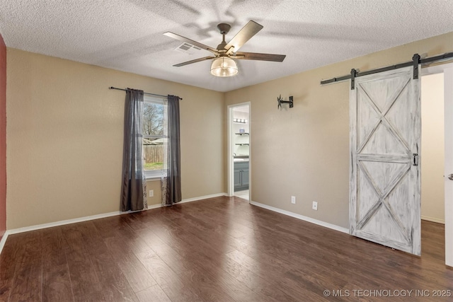 unfurnished room with a barn door, baseboards, wood finished floors, and a ceiling fan