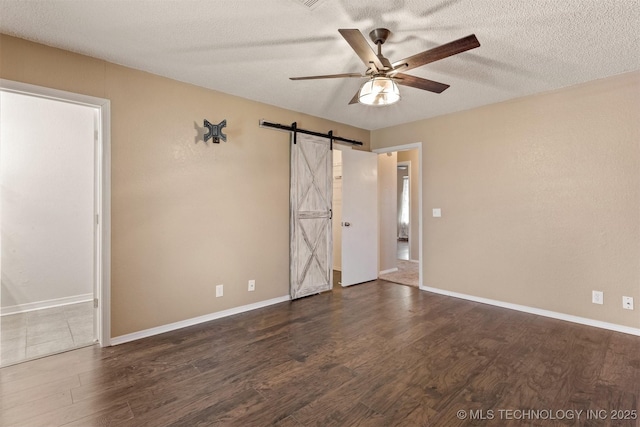 spare room featuring a textured ceiling, a barn door, and wood finished floors